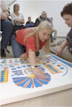 A visitor is using her hands to explore a tactile object representing Henri Matisse's painting Apollo.